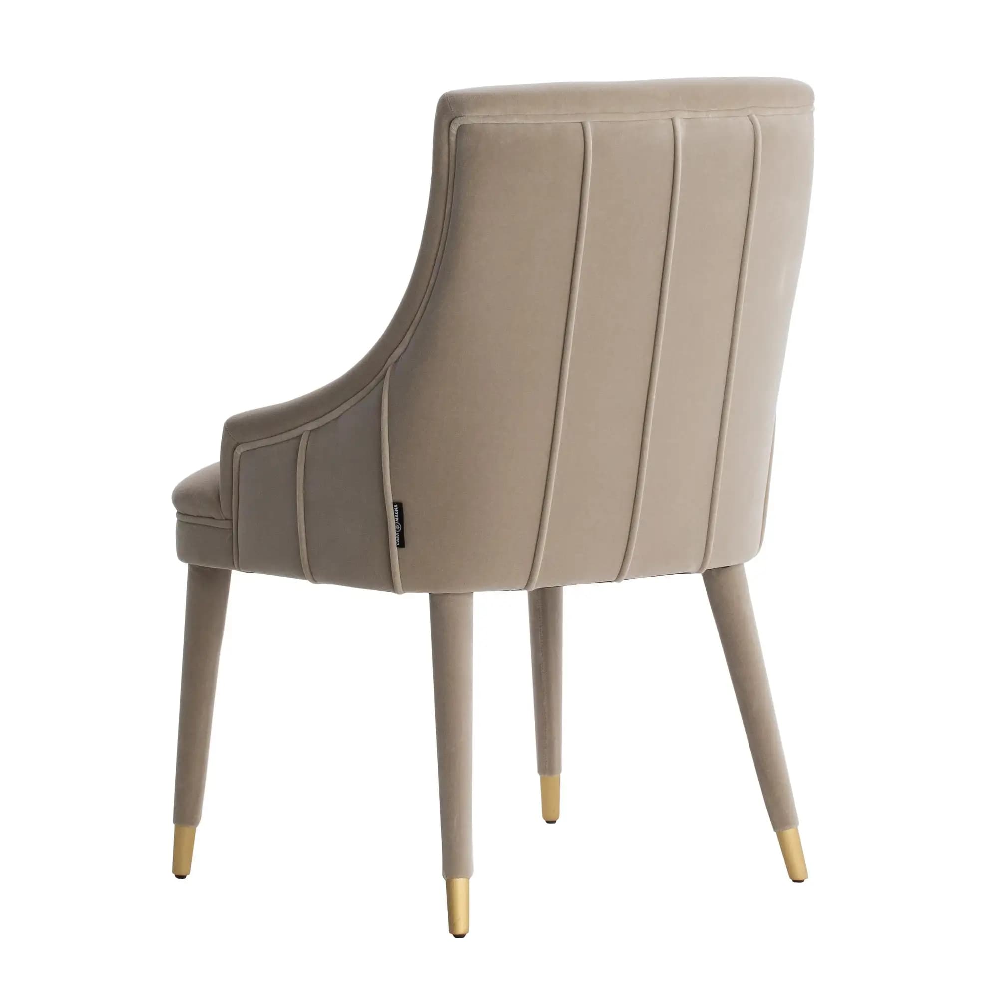 An upholstered armchair, seen from the rear, featuring a high back with vertical channel tufting. The chair is covered in a smooth, light beige or taupe velvet-like fabric. It has low, integrated armrests. The legs are slender, tapered, and wrapped in the same fabric, with gold-finished caps on the feet. — 3D model