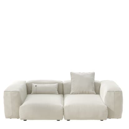 A light beige, two-piece modular sectional sofa featuring a chaise lounge component and an armless seating module with an integrated armrest on the right. The sofa is upholstered in a soft fabric with rounded edges, exuding a contemporary and relaxed aesthetic. It includes two matching throw pillows. — 3D model