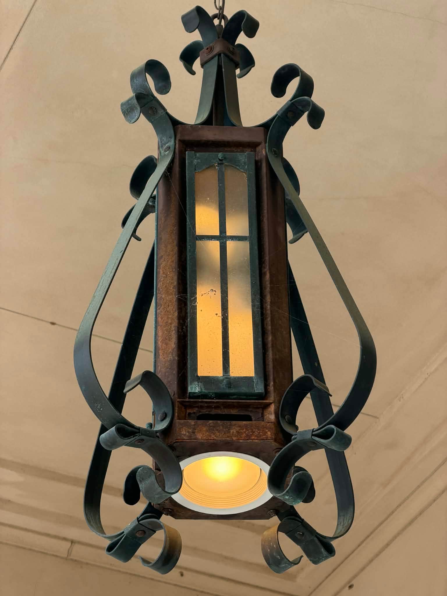 An ornate hanging lantern made of dark wrought iron and rusted metal, featuring frosted glass panels… — 3D model
