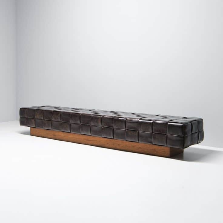 A long, rectangular bench with a woven leather seat and a wooden base. The seat features a grid patt… — 3D model