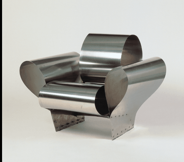 An avant-garde armchair constructed from curved, polished metal sheets. The design features a prominent, rounded backrest and armrests that flow seamlessly from the seat. The base is formed by angular metal plates riveted to the main structure. — 3D model