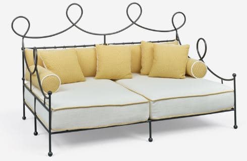A decorative metal sofa with a dark finish and scrollwork on the backrest. It features thick white seat cushions with yellow piping and multiple yellow throw pillows and bolsters. — 3D model