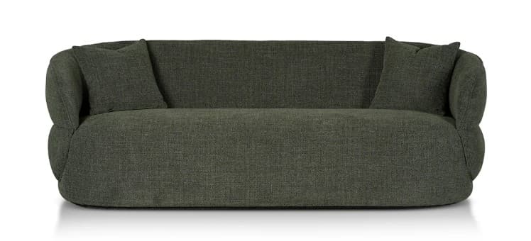A sofa with a plush, rounded design and integrated armrests. The sofa features a deep seat and a high back, upholstered in a textured, dark green fabric. Two matching throw pillows are placed on the sofa. The base of the sofa is low-profile and appears to be integrated into the overall rounded form. — 3D model