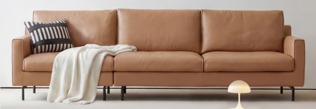 A modern three-seater sofa upholstered in tan-colored leather or faux leather, featuring a minimalist design with clean lines, square armrests, and slender black metal legs. The sofa consists of three individual seat cushions and three matching back cushions, providing a streamlined and contemporary aesthetic. The overall condition appears new. — 3D model