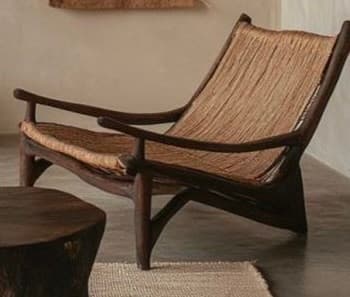 A modern armchair featuring a dark wood frame with gracefully curved legs and armrests. The seat and back are constructed from tightly woven natural fiber material, giving it a textured appearance. — 3D model