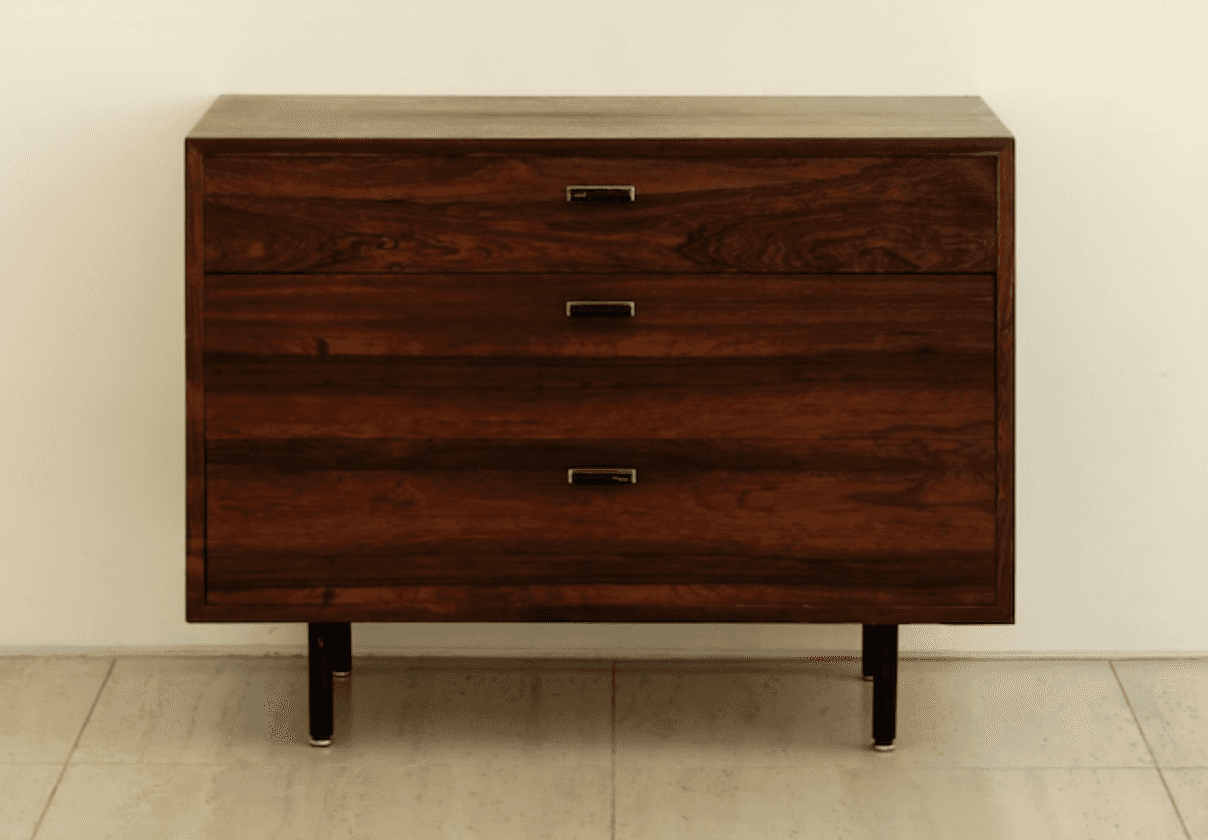 A dark wooden chest of three drawers with slender black legs and minimalist metal handles, set again… — 3D model