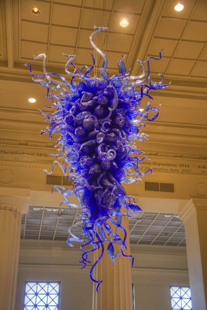 A large, elaborate chandelier constructed from numerous individual pieces of hand-blown art glass. The fixture features a voluminous, cascading form composed primarily of deep cobalt blue glass elements, including swirling tendrils, bulbous forms, and some leaf-like shapes, creating an organic and sculptural aesthetic. — 3D model