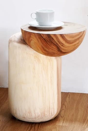 A visually striking end table featuring two distinct wooden components. The base is a solid, cylindrical form with a rounded bottom and a light, almost white, wood finish that highlights vertical grain patterns. Perched atop the base is a semicircular or bowl-shaped top with a rich, natural wood grain in warm brown tones. A white ceramic teacup and saucer are placed on the wooden top. — 3D model
