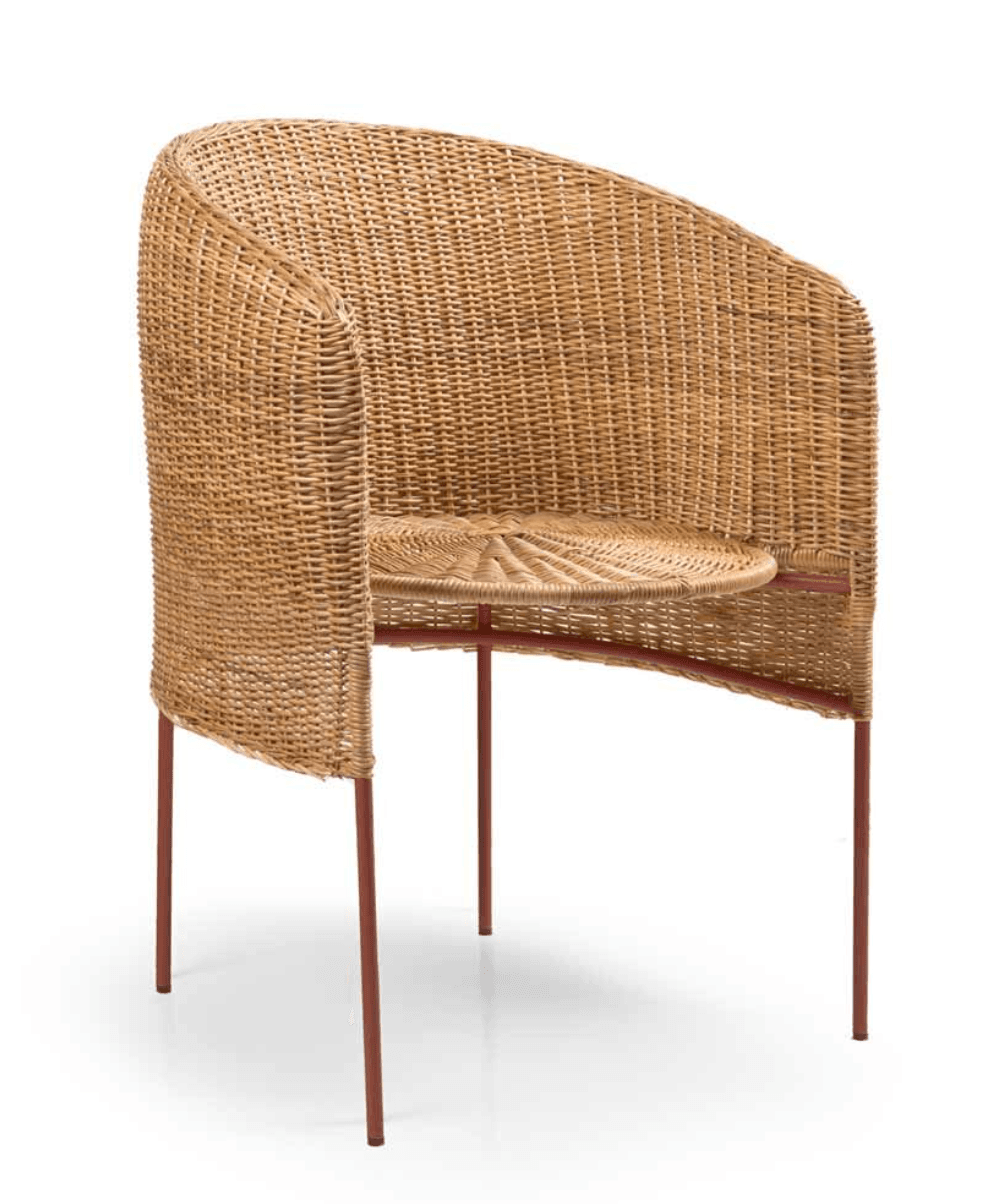 A contemporary barrel-shaped armchair featuring a natural woven rattan body and a minimalist metal leg structure. The chair has a rounded backrest that flows into integrated armrests, and a circular seat cushion is formed from the same woven material. The slender, tapered legs are made of metal with a reddish-brown finish, providing a modern contrast to the organic texture of the rattan. — 3D model