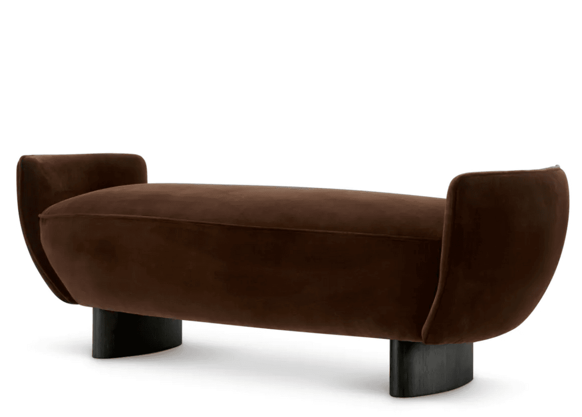A contemporary bench upholstered in rich brown velvet, featuring a long, subtly curved seat and distinctive, upward-curving end sections that act as low armrests or back supports. It stands on two solid, dark-colored, vertically oriented block legs that are also gently curved. — 3D model