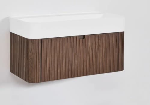 A modern wall-mounted bathroom vanity featuring a rectangular white integrated sink top with gently rounded corners, situated above a fluted dark brown wooden cabinet. The cabinet has a minimalist design with a single door or drawer front featuring a subtle integrated finger pull handle. — 3D model