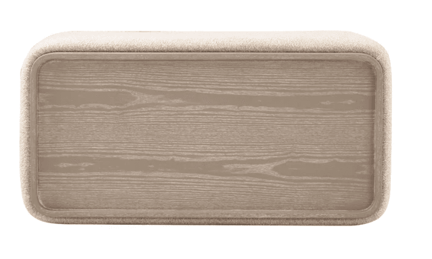 A rectangular upholstered ottoman featuring gently rounded corners and a soft, textured fabric top and frame. The sides are adorned with recessed panels showcasing a light-colored wood grain finish, creating a contrast in texture and material. — 3D model