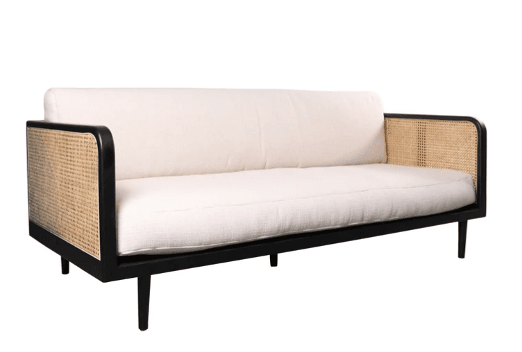A modern three-seater sofa featuring a sleek black wooden frame and natural cane detailing on the armrests, complemented by light-colored fabric cushions. The design is clean-lined with tapered legs. — 3D model