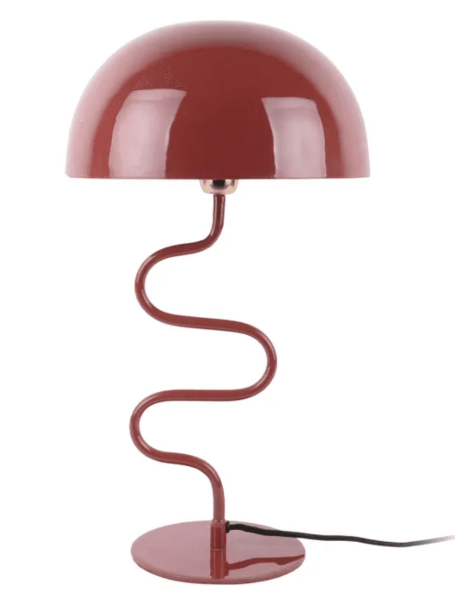 A modern table lamp featuring a monochromatic burgundy red finish. It has a smooth, dome-shaped shade and a distinctive wavy, serpentine stem that rises from a circular base. The design is playful and sculptural, with a simple black power cord extending from the base. — 3D model