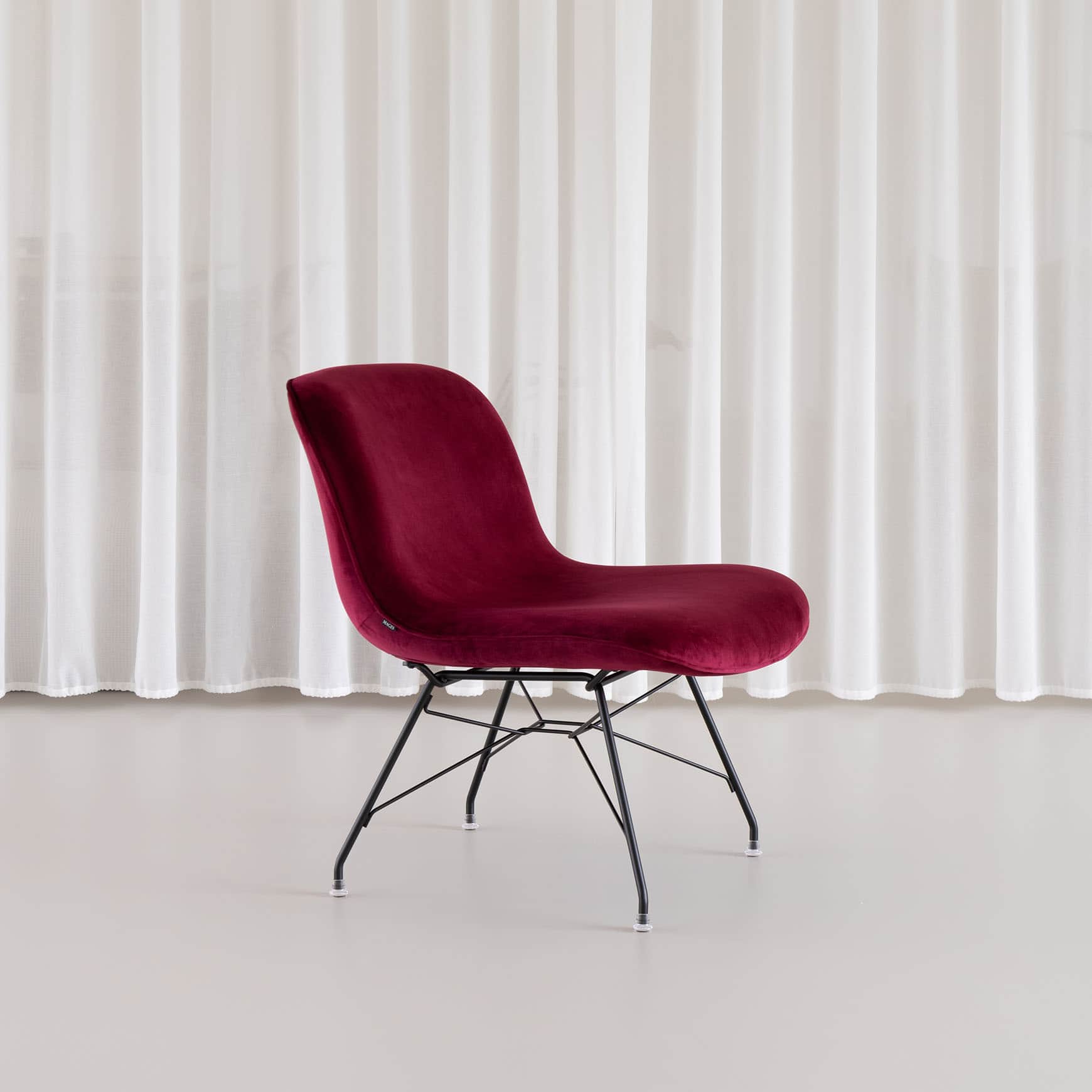 A modern armless chair upholstered in deep red velvet, featuring a shell-shaped seat and back, suppo… — 3D model