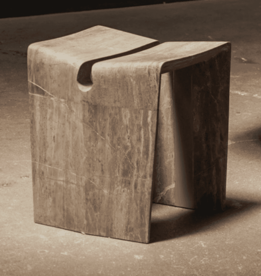A small, contemporary sculptural stool crafted from natural marble, featuring a monolithic, curved f… — 3D model