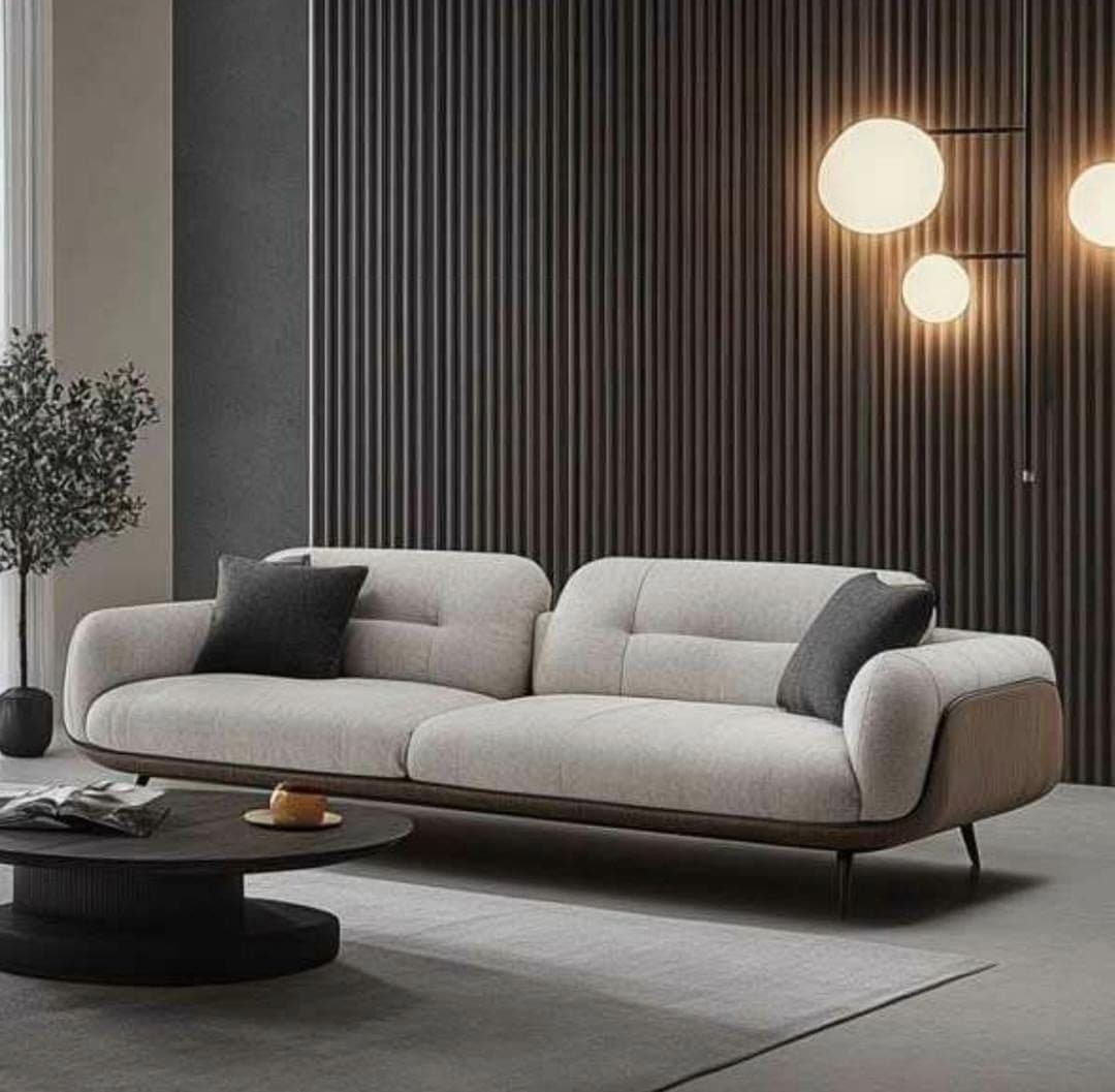 A contemporary two-seater sofa featuring a light beige fabric upholstery for the main body and seat cushions, contrasted with rich brown leather on the outer frame, including the armrests and lower perimeter. The sofa rests on slender, tapered black metal legs and includes two dark gray accent pillows. — 3D model