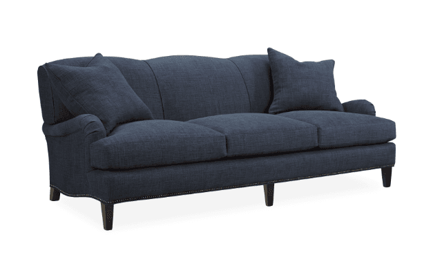 A three-seater sofa upholstered in a dark blue textured fabric. The sofa features a curved backrest with vertical channel tufting and rolled arms. It is supported by short, dark wooden legs. Decorative nailhead trim runs along the base of the sofa. Two throw pillows, matching the upholstery, are present, one on each end of the sofa. — 3D model