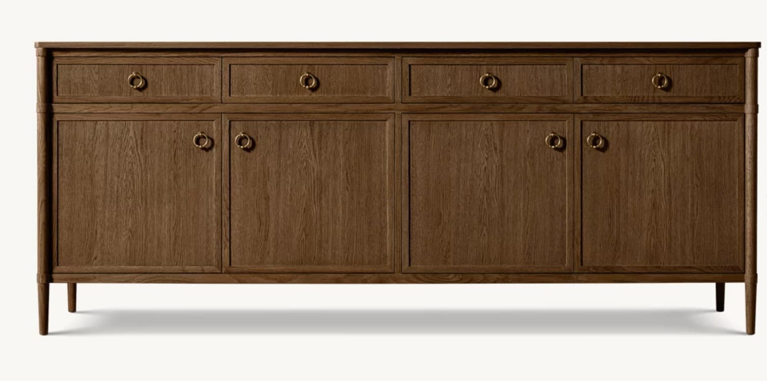 A long, low wooden credenza featuring a dark brown finish with visible wood grain. The credenza is supported by four tapered legs and comprises multiple storage compartments. The upper section includes several drawers, each fitted with a circular brass ring pull. Below the drawers are multiple sets of double doors, each also adorned with brass ring pulls, indicating enclosed storage. The design exhibits clean lines and a functional aesthetic. — 3D model