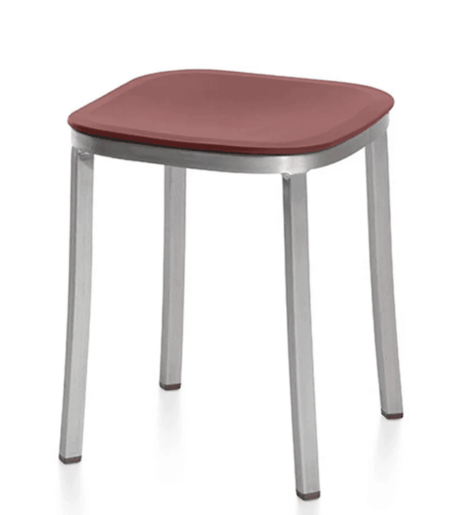 A stool with a square-ish, slightly rounded seat and four metallic legs. The seat appears to be made of a solid material with a matte finish, and the legs are slender and angled. The stool has a modern and minimalist design. — 3D model