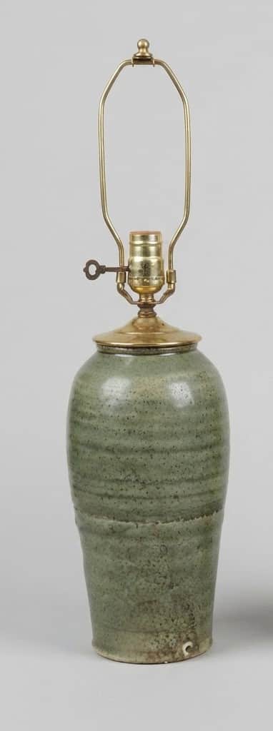 A close-up, eye-level shot of a ceramic table lamp base with brass hardware. The lamp base is a stur… — 3D model