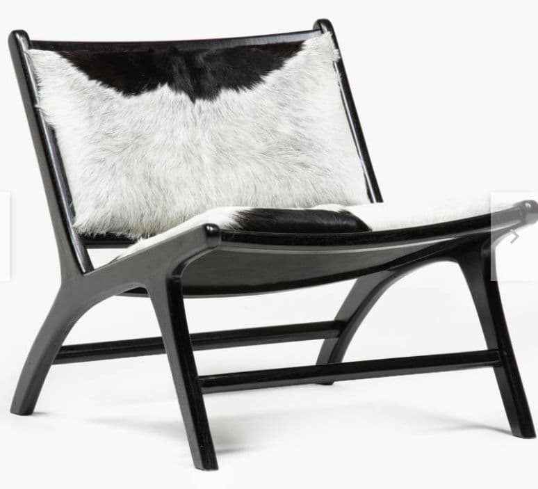 An armless lounge chair featuring a low-slung black wooden frame and upholstery made from genuine black and white cowhide. The chair has a minimalist design with a reclined backrest and a wide seat, supported by a sturdy, curved wooden frame. — 3D model