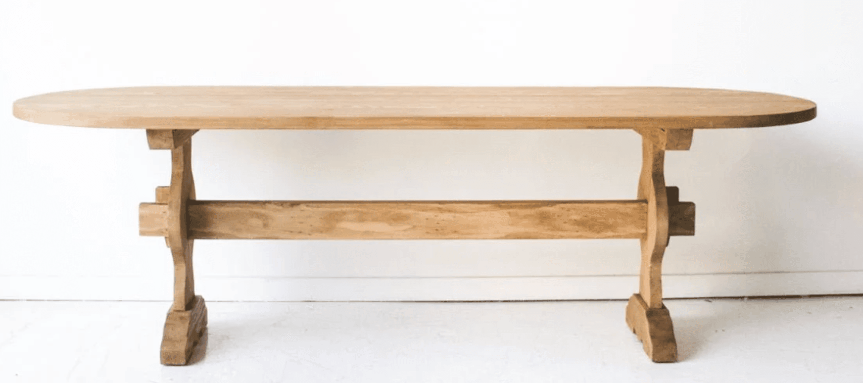An oval dining table constructed from light-toned wood, featuring a distinctive trestle base. The tabletop is smooth and has rounded edges, while the base consists of two pedestals connected by a stretcher, presenting a sturdy and classic design. — 3D model