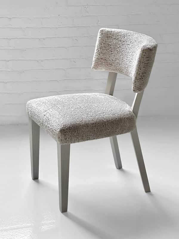 An armless dining chair featuring a light-colored, textured upholstered seat and a distinctively cur… — 3D model