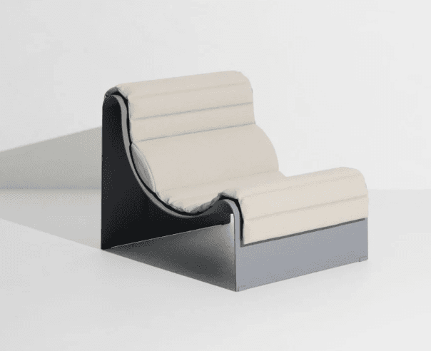 A modern armchair with a distinct architectural form. It features a dark gray, angular base and frame that supports a cushioned seat and backrest. The upholstery is a light, neutral color, possibly beige or off-white, with a textured, tufted appearance. The design emphasizes clean lines and geometric shapes, suggesting a contemporary or postmodern aesthetic. — 3D model