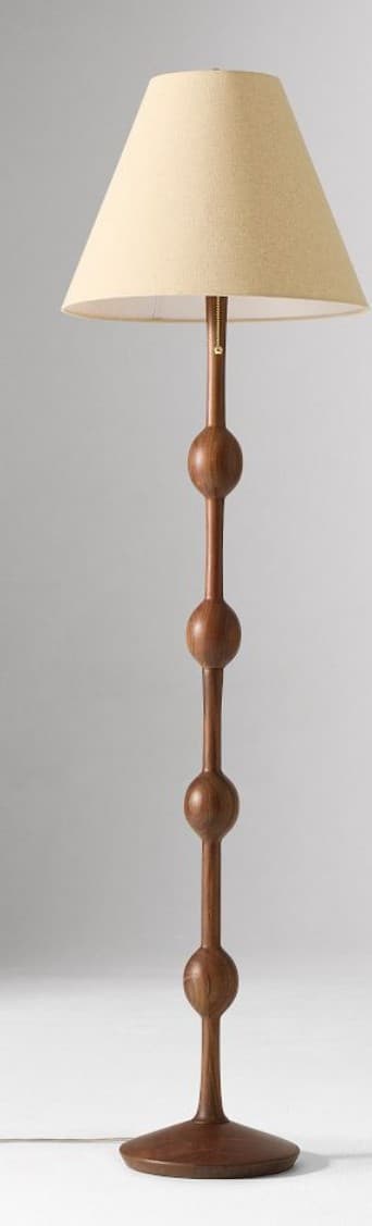 A tall, sculptural floor lamp featuring a dark wood stem with several interspersed spherical turnings, resting on a wide, flat disk base. It is topped with a conical, light-colored fabric lampshade. — 3D model
