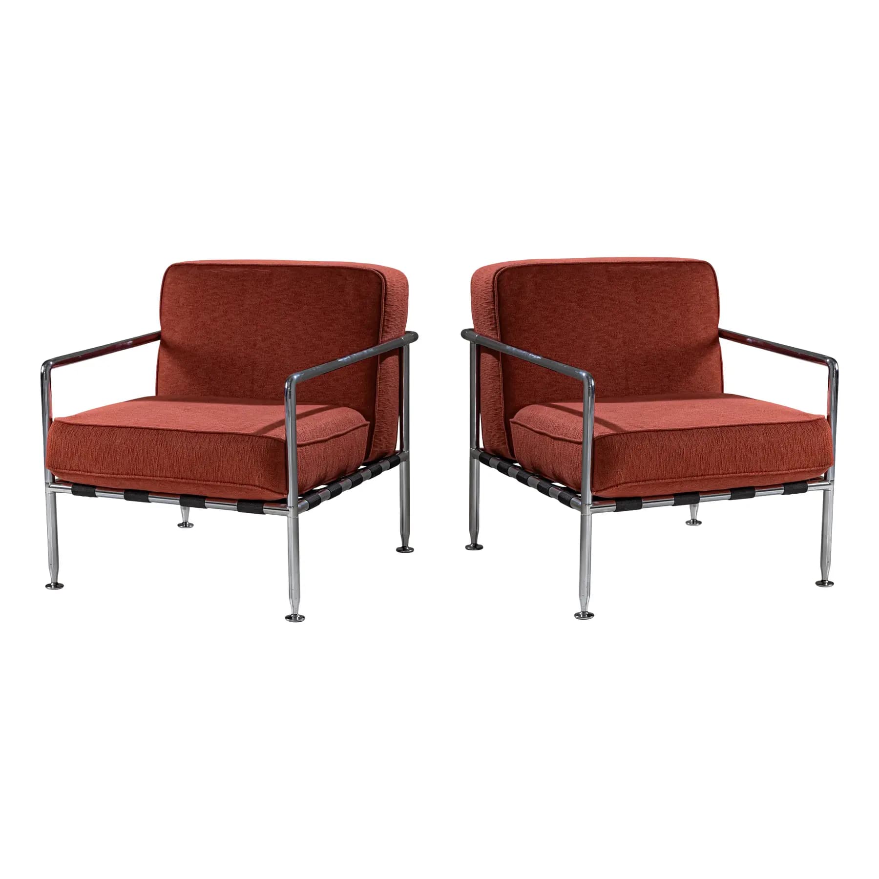 A pair of armchairs with a modern design. Each chair features a polished chrome frame, including the armrests and legs. The seating and back cushions are upholstered in a textured, rust-colored fabric. The seat support appears to be constructed from woven straps. The chairs have a minimalist aesthetic, emphasizing clean lines and industrial materials. — 3D model