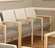 A modern armchair with a light wood frame and grey upholstered seat and backrest. The armchair features a simple, clean design with straight lines and slightly rounded edges on the wooden components. It has four straight legs and integrated armrests that are part of the frame. — 3D model