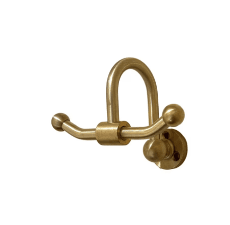 A wall-mounted coat rack constructed from solid brass, featuring a distinctive U-shaped top hook and two lower horizontal hooks that extend outwards, each capped with a spherical end. The design includes a circular mounting plate with visible screw holes, indicating a secure attachment to a wall. The brass exhibits a warm, golden tone with a slightly aged or brushed finish. — 3D model