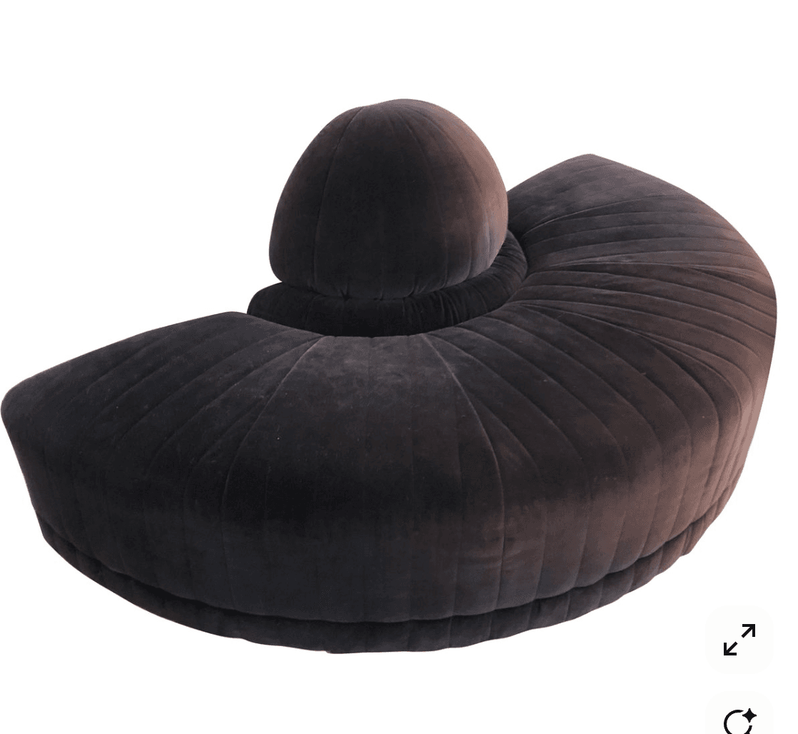A contemporary, curved sofa upholstered in a dark grey or charcoal velvet fabric, featuring prominent channel tufting across its entire surface. The sofa has a distinctive spherical or dome-shaped backrest element integrated into its center, providing a unique visual focal point. Its form suggests a plush and luxurious seating experience. — 3D model