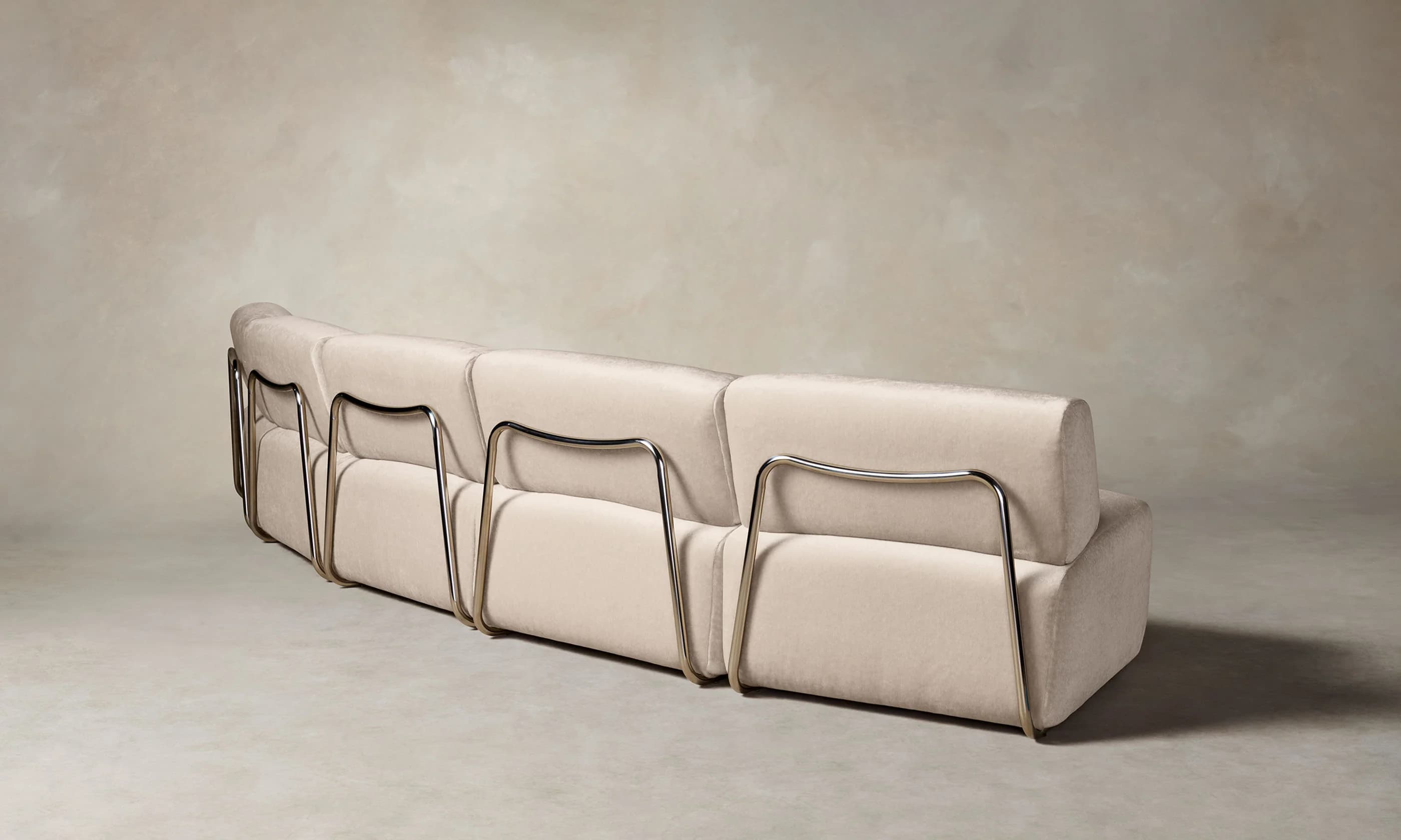 A contemporary three-seater sofa featuring a light-colored fabric upholstery and a distinctive exposed tubular metal frame that supports the backrest and forms the legs. — 3D model