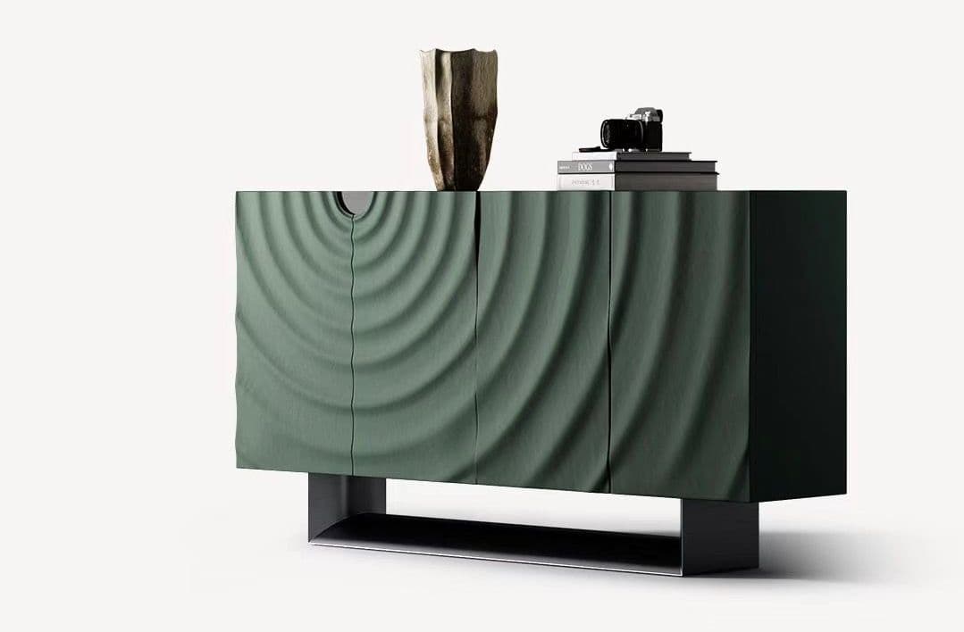 A modern sideboard with a distinctive front panel featuring a deeply grooved, concentric ripple pattern. It has a dark green finish and stands on a minimalist black metal base. The top surface displays decorative objects: a textured vase and a stack of books topped with a camera. — 3D model