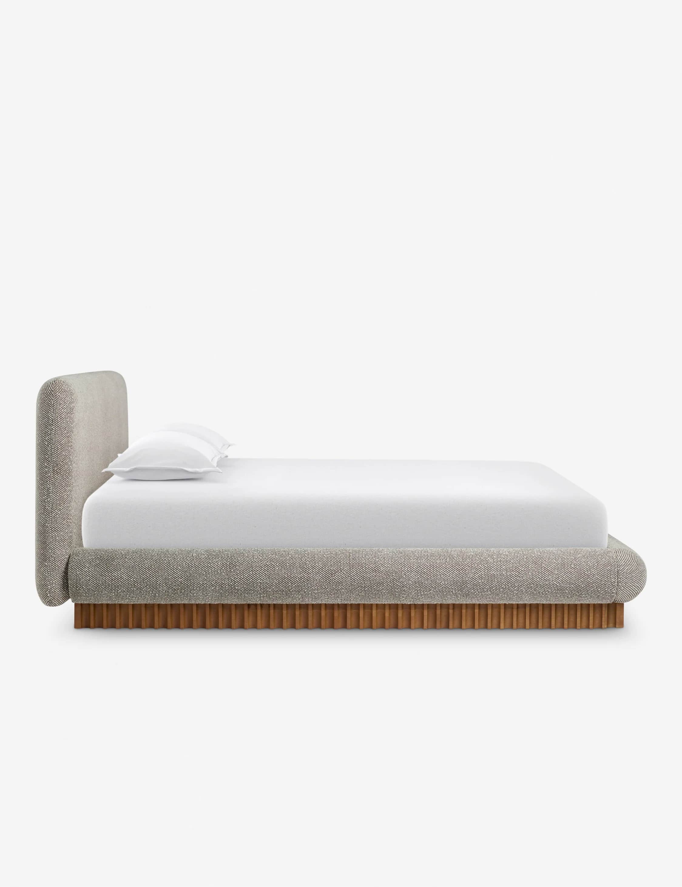 A side profile view of a modern upholstered bed with a curved headboard and a wooden slatted base. T… — 3D model