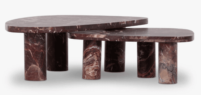 A set of two nesting tables crafted from reddish-brown marble, featuring distinct white, grey, and black veining. The tables have rounded tabletops—one appearing semicircular and the other an elongated oval—supported by robust cylindrical marble legs. — 3D model