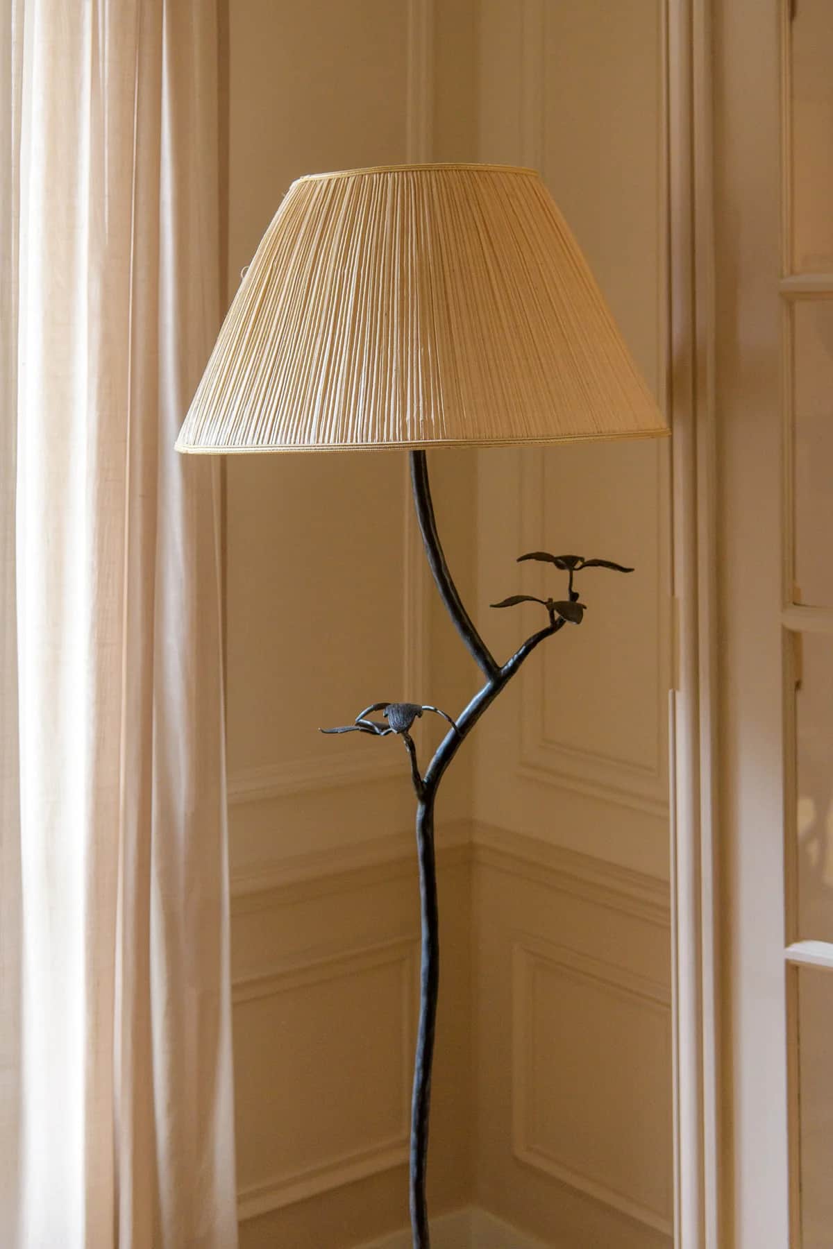 A tall floor lamp featuring a dark-finished metal stem adorned with decorative leaf accents and a st… — 3D model