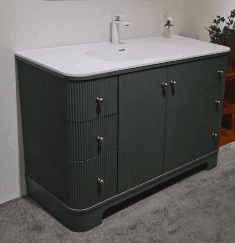 A modern dark green bathroom vanity featuring a fluted cabinet design, an integrated white ceramic s… — 3D model