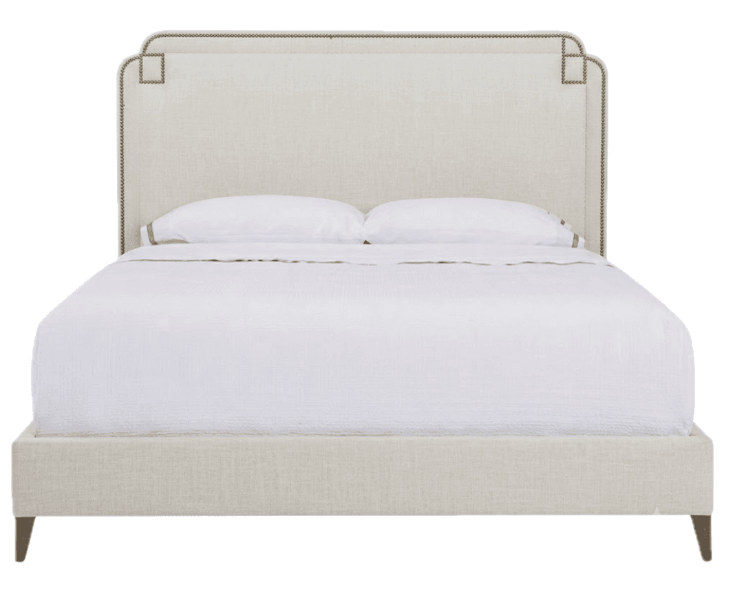 A contemporary upholstered bed featuring a distinctive headboard and a matching upholstered frame. The headboard has a gently curved top edge with subtle cutouts and is adorned with a continuous line of brass or bronze nailhead trim, which also forms decorative square accents at the upper corners. The entire bed frame, including the side rails and footboard, is upholstered in a light, neutral-toned fabric. The bed is supported by four dark, tapered wooden legs and is presented with white bedding. — 3D model