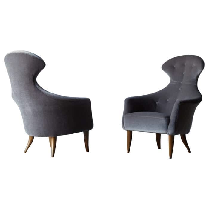 A mid-century modern inspired armchair with a high, sculpted backrest and tufted detailing. The chair features upholstered arms and is supported by four tapered wooden legs. — 3D model