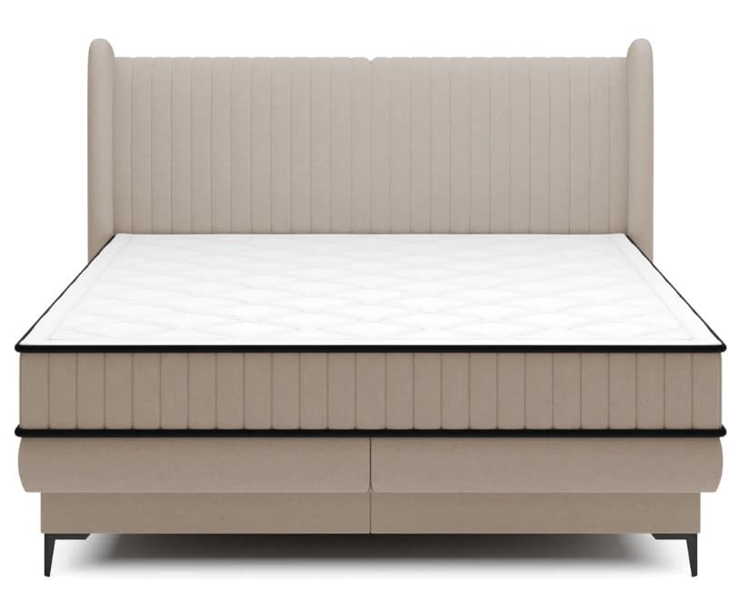A contemporary upholstered bed featuring a distinctive wingback headboard and an integrated box spring base. The entire structure, including the headboard and base, is covered in a soft beige fabric with vertical channel tufting on the headboard and upper box spring. The bed is supported by subtle, tapered black metal feet. A white mattress with black piping is positioned on top of the box spring. — 3D model