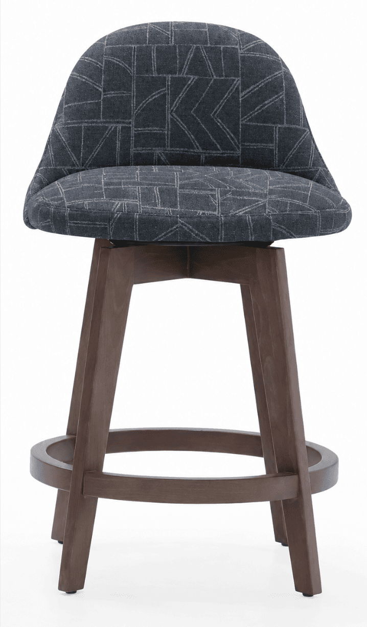 A bar stool with a upholstered seat and back, featuring a curved backrest and a solid wood base. The seat and back are covered in a dark gray fabric with a geometric pattern in a lighter gray. The base consists of four angled wooden legs connected by a circular footrest. The stool appears to be designed for counter or bar height seating. — 3D model