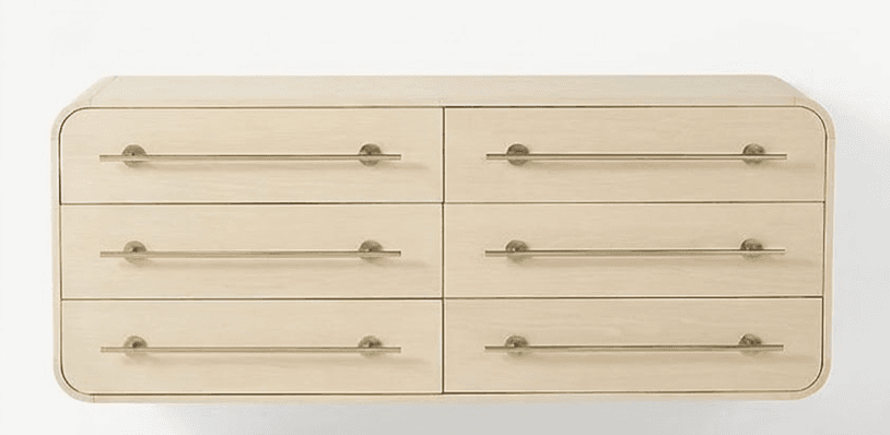 A contemporary six-drawer dresser constructed from light-toned wood, possibly maple or ash, featuring a minimalist design with distinctive rounded edges on its top, bottom, and side panels. Each drawer is equipped with a slender, horizontally mounted brass bar pull, contributing to its sleek aesthetic. The dresser presents a clean and modern silhouette. — 3D model