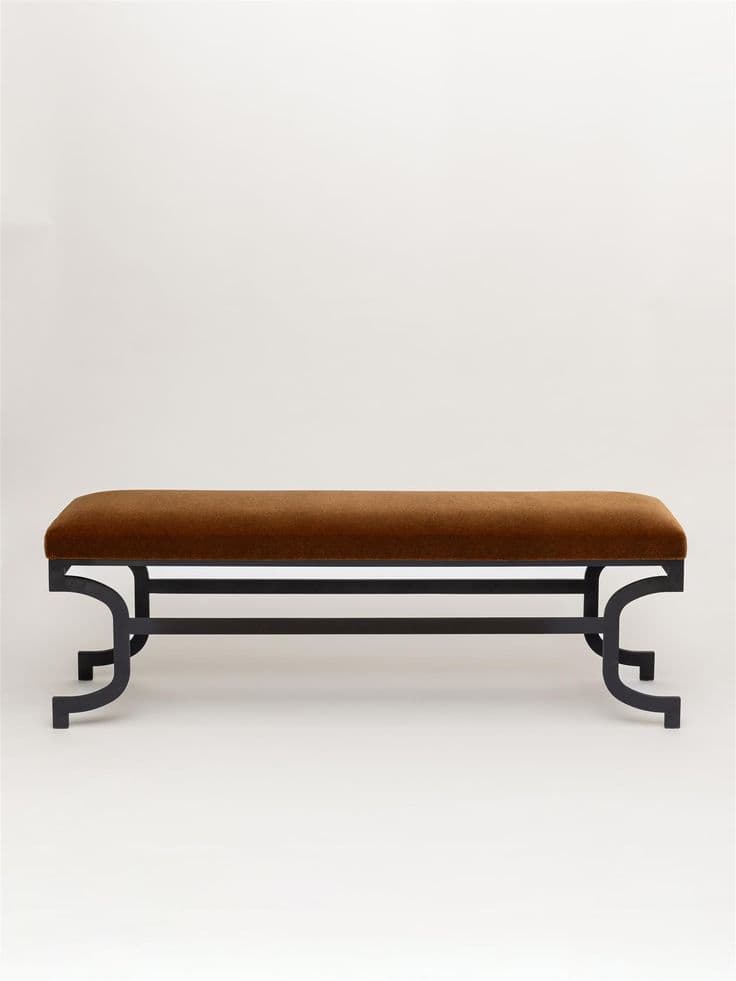 A long, rectangular upholstered bench featuring a plush, dark brown velvet seat and a black powder-coated metal frame. The frame is distinguished by its decorative, curvilinear leg supports on either end, connected by two parallel horizontal bars. The overall aesthetic is refined and blends classic design elements with a contemporary finish. — 3D model