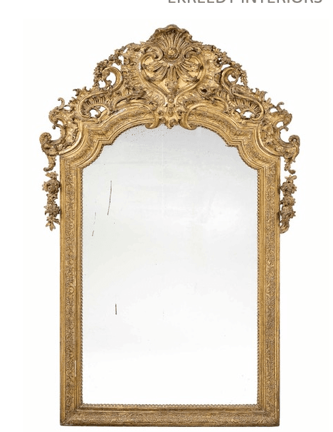 A large, ornate gilded mirror featuring an elaborate Rococo-style frame and crest. The frame is intricately carved with scrolls, floral motifs, and shell-like designs, all finished in gold. The mirror glass shows signs of age with some imperfections. — 3D model