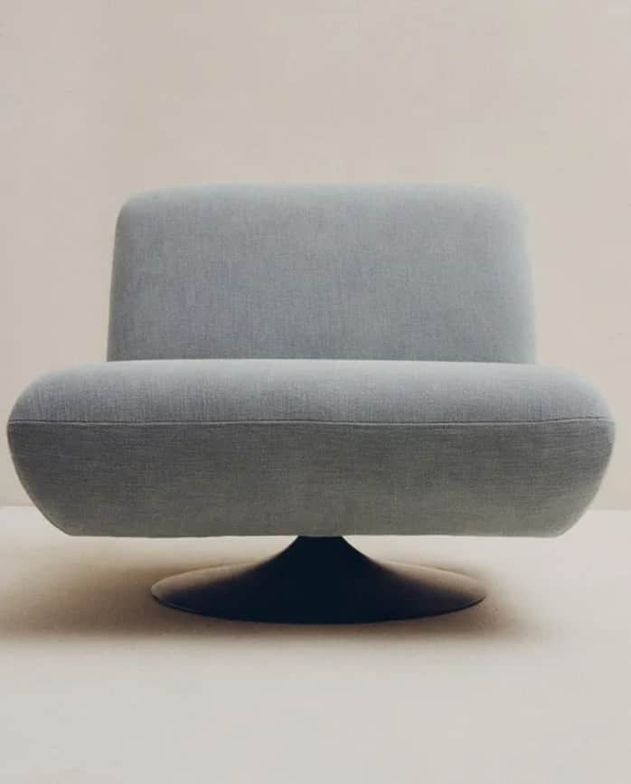 A light blue, heavily padded swivel lounge chair featuring a minimalist, sculptural form and a dark,… — 3D model