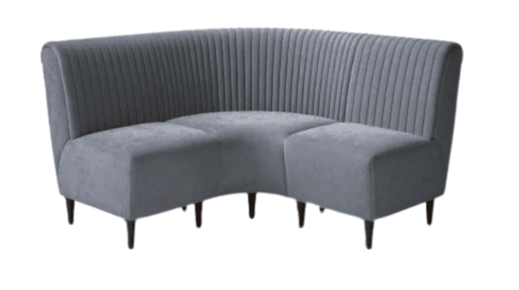 A curved, upholstered sectional sofa with a fluted backrest and a padded seat. The sofa is supported by four dark-toned wooden legs. The overall shape suggests a contemporary design with a focus on comfort and aesthetics, suitable for lounges or dining areas. — 3D model