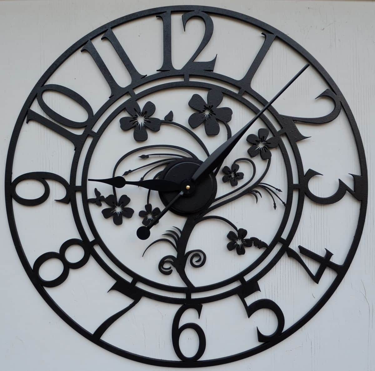 This is an ornate circular wall clock crafted from black metal, featuring an open-face design. The c… — 3D model
